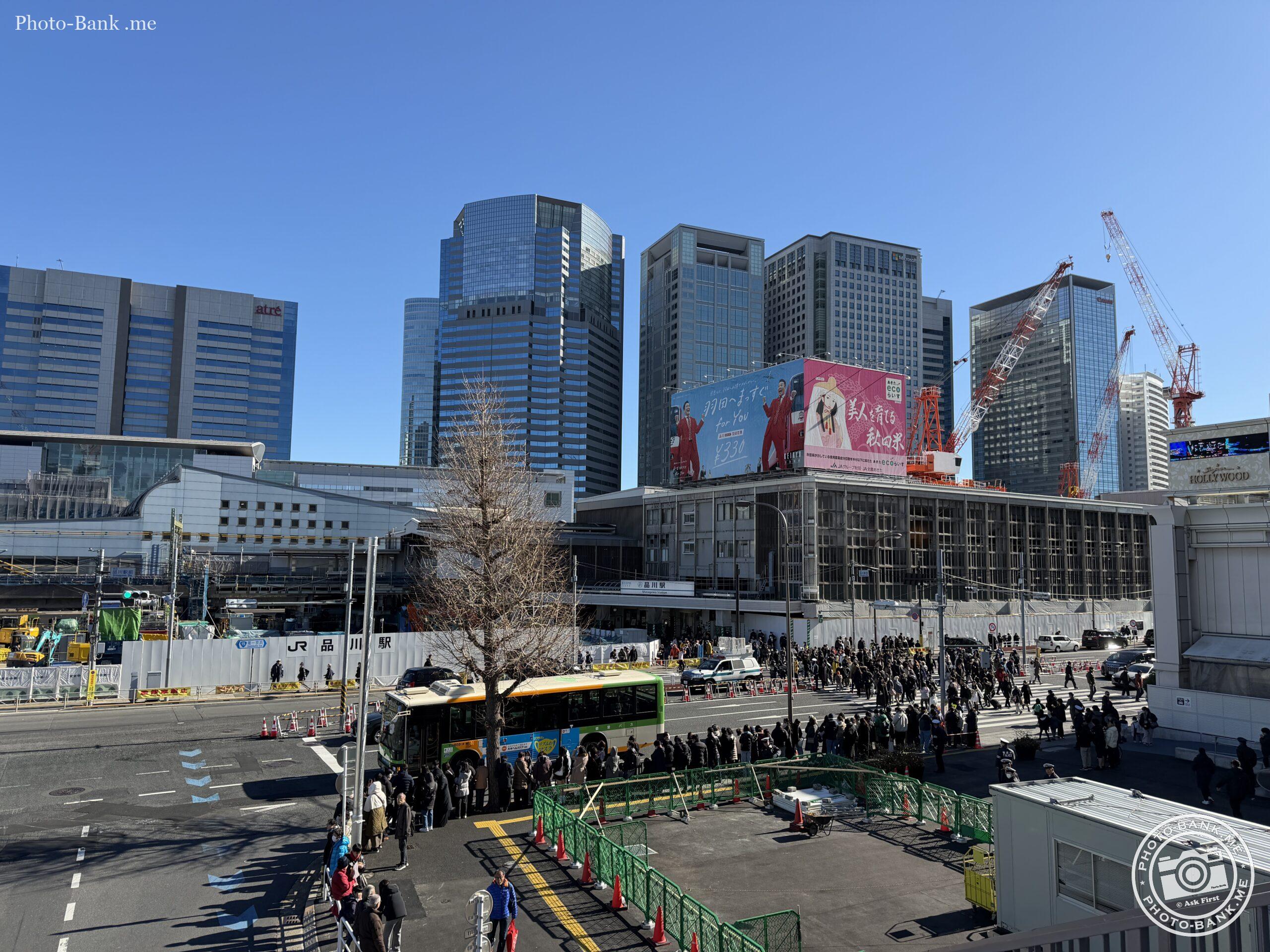 再開発中の品川駅高輪口、駅前広場にはバスを待つ人々や工事現場が見える