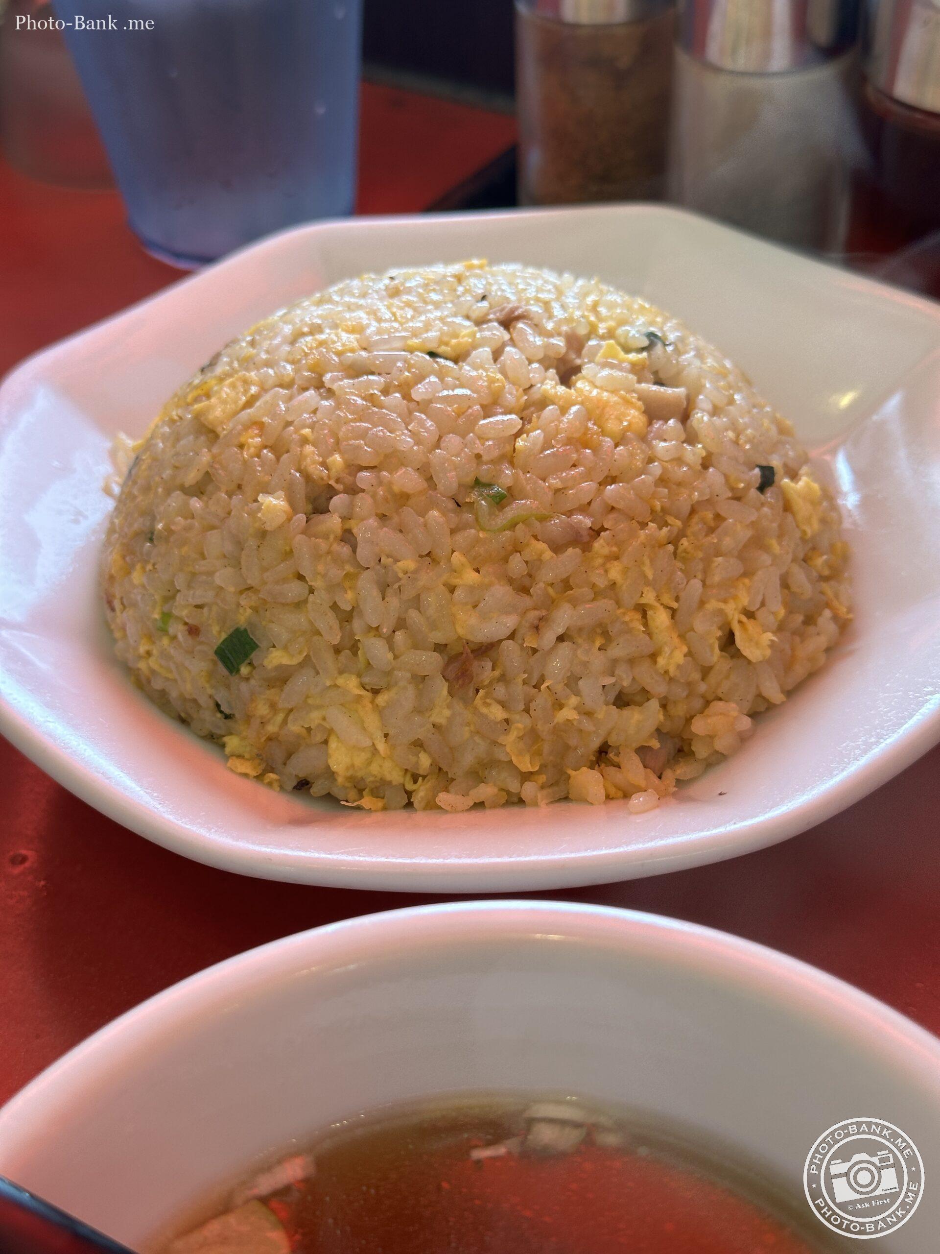 熱々の炒飯が湯気をまとって輝いている。白い皿に盛られた炒飯とスープ。