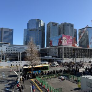 再開発中の品川駅高輪口、駅前広場にはバスを待つ人々や工事現場が見える
