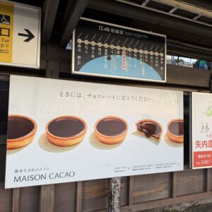 江ノ電鎌倉高校前駅にて、MAISON CACAOのチョコレートタルト広告と江ノ電路線図を撮影。