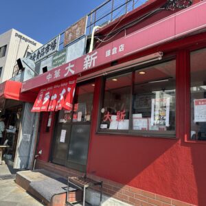 神奈川県鎌倉市の中華大新 鎌倉店の赤い外観とラーメンの暖簾、周辺の看板を捉えた写真