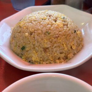 熱々の炒飯が湯気をまとって輝いている。白い皿に盛られた炒飯とスープ。