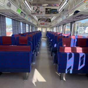 京急電鉄の車内、青と赤の座席が整然と並び、車窓からは住宅街が見える。
