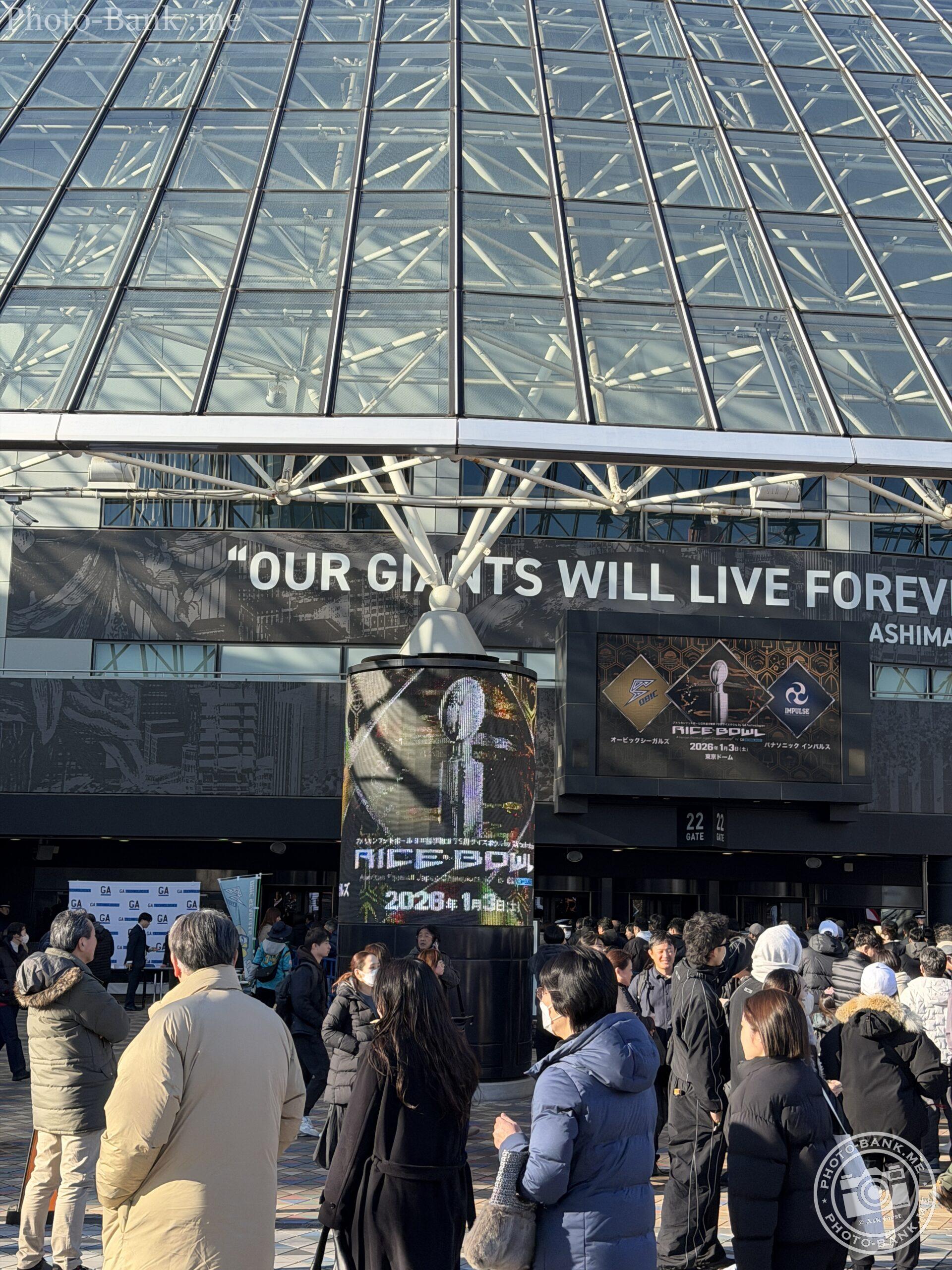 東京ドームのガラス張りの壁面とライスボウルの広告、そして観戦を待つ人々